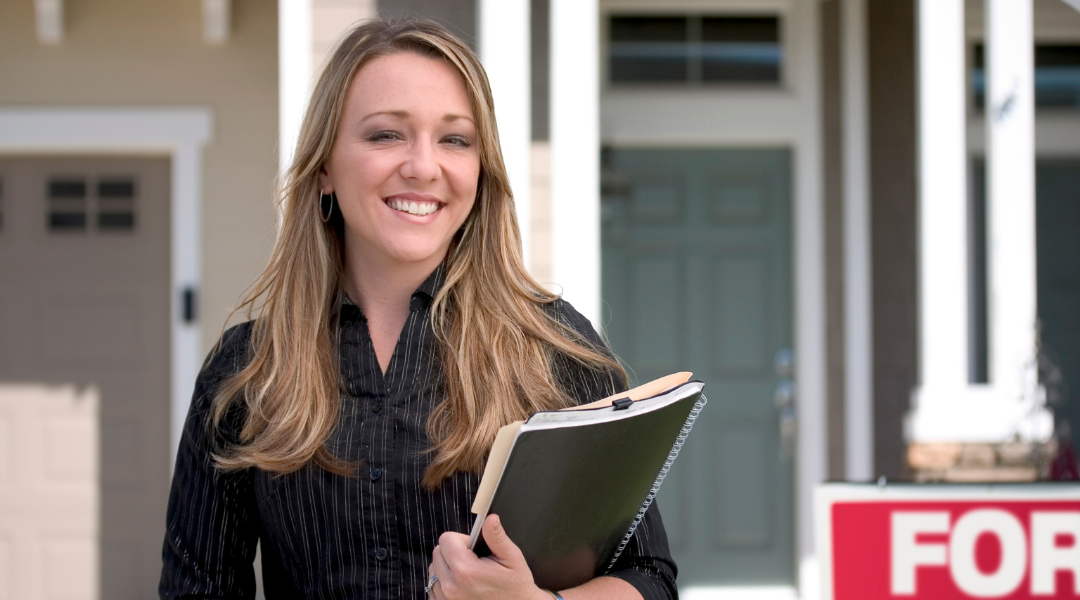 Professional real estate agent with folder standing in front of house for sale